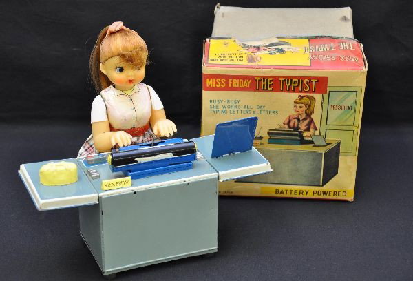 Boxed Miss Friday the Typist Battery Toy: TN Japan, litho tin with vinyl head, battery operated, functional. Hands and head move, typewriter pecks and returns with a bell, great action! Shows light playwear with nice original box, C7+
