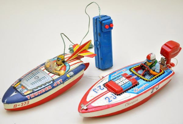 Japanese Tin Racing Boats: 10" Bandai Thunder Jet Boat, battery operated functioning, controller has a few dents. 12" Champion Boat by SAN, battery operated, removable plastic Neptune motor is functioning. Both show light to mo