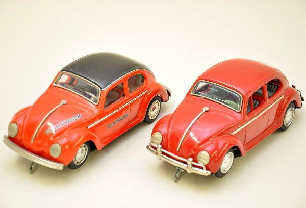 2 Super Japanese Tin VW Beetle Cars: Both by Taiyo, Japan, 9 1/2" long, battery operated and functional, red car with driver is mid 1960s and like-new, while the red and black is late 1960s design and shows light playwear. Both are clean