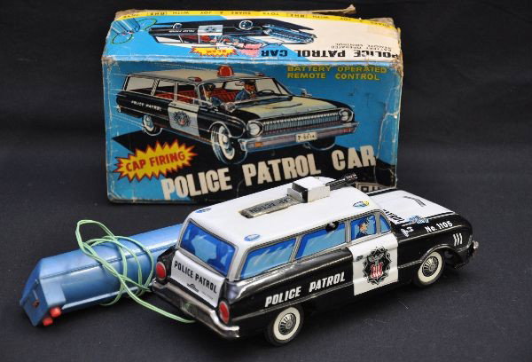 Unusual Boxed Cap Firing Police Car: AHI Japan, 9" long, Ford styling, battery operated, tethered forward and reverse, lighted gun & cap firing action, functional (not guaranteed), with worn original box. Shows very light playwear, C8