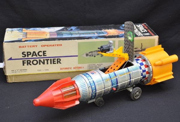 Boxed Space Rocket Battery Toy: KY Japan, 18" long, litho tin & plastic, functional (not guaranteed), mystery action with spinning and lighted front and rear sections, stops and astronaut rises up when hatch opens to fire gun, very 