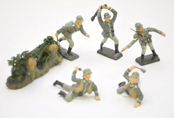 Composition German Soldier Lot: Schusso clubbing figure and damaged grenade figure, 3 Lineol grenade figures and a foliage piece. All show light signs of use, clean and shiny. C7-8
