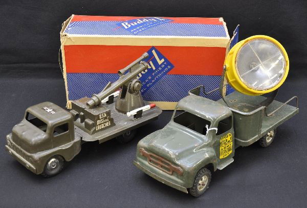 Structo and Buddy L Army Trucks: 13" Structo missile launcher with two original missiles, missing cocking lever, C7; Buddy L searchlight truck, some battery damage inside. Shows moderate to heavy playwear but has a nice original box,