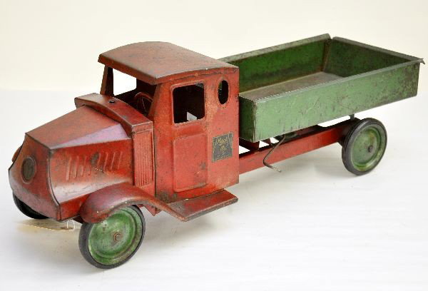 Metal Craft Mack Dump Truck: Nice model of the bulldog Mack truck, circa 1920's, painted pressed steel with wooden tires, 22" long, original decals are 95%. Shows moderate to heavy playwear, some staining to back, C5