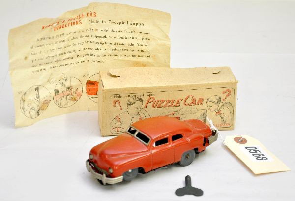 Unusual Occupied Japan Puzzle Car: Enameled tin, 6" long, mechanism is functional with key and instructions, has mystery action, shows light playwear but unfortunately is faded one side, rare original box. Otherwise, C7+-8