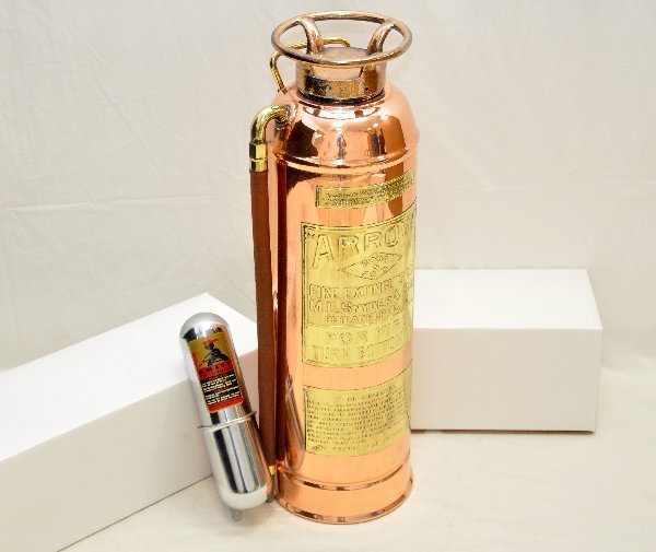 2 Early Fire Extinguishers: 9" Amity hand-held with holder; 21" copper Arrow, soda & acid version. Both are in great shape, showing light signs of use & age. .
