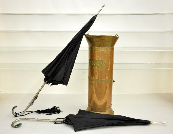 2 Ornate Early Umbrellas with Copper Stand: Circa 1930s, 40s; Beautiful black umbrellas, one with cast leaf motif & green plastic jewel; the other has a floral pattern with 3 plastic red jewels, both function and have worn covers. Also included