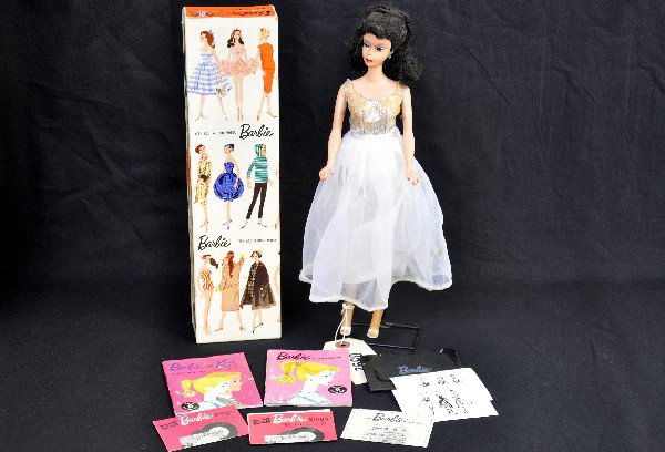 Boxed 1959 Barbie Doll: Model 850 Hard Plastic body, vinyl head with swivel and jointed limbs, rooted black hair in ponytail with curly bangs, painted features, painted eyebrows, blue eyes with white iris, red nails and lips