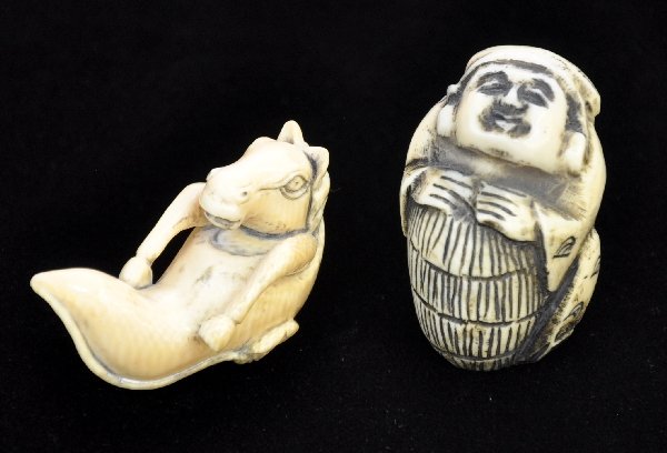 2 Carved Ivory Netsukes: One is a seated male figure holding a barrel. The other is an adorable horse emerging from a lotus blossom with carved leaves on bottom. Both are well carved with black stained for contrast and signed