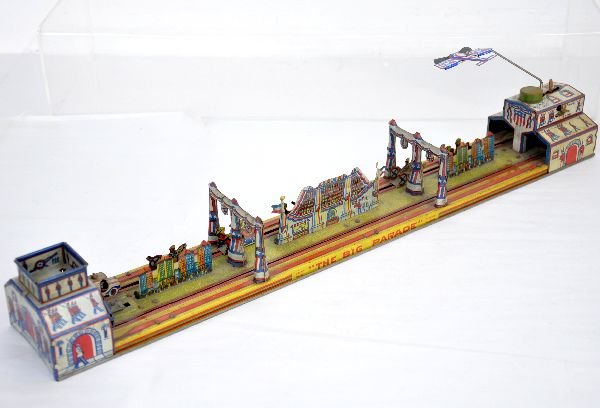 Marx The Big Parade Wind-up Toy: 24" litho tin, mechanism functions (needs lubrication), though string slips. It is complete with the airplane and all accessory pieces. The litho is rich in color and it shows light to moderate playwe