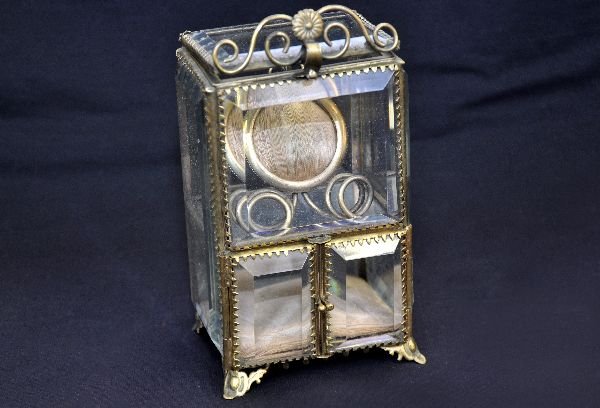 Glass & Bronze Watch Box: Super Victorian watch box or safe. 3 1/4X2 1/4X 6". Beveled glass with ornate bronze frame. Inside has a padded pin cushion style holder on top with a padded flat base shirtboard. It is in nice condit