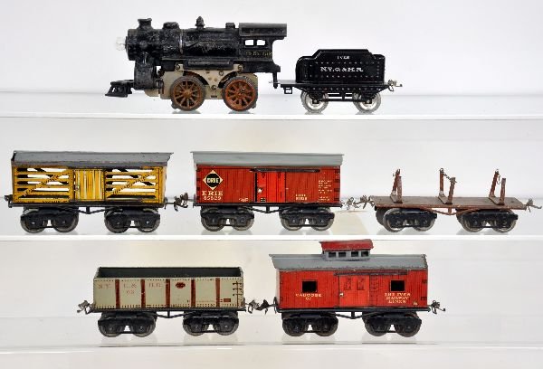 7Pc Ives Freight Set: Includes a 1118 electric steam loco; restored 11 tender; 63 sand car; 61 lumber, 1 complete chain; 64 Erie boxcar, roof restored; 65 stock car; 67 caboose. All show moderate playwear, otherwise C6