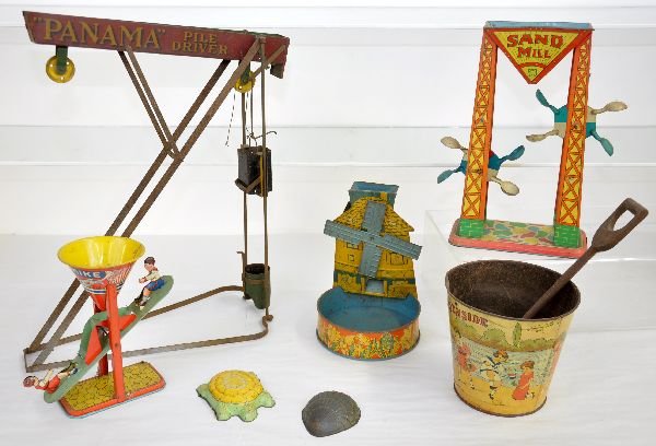 Early Tin Sand Toys Lot: Includes a Panama Pile Driver, missing counter weight, C4; 11 1/2" Chein Sand Mill; Chein Busy Mike; T. Cohn Windmill with tray; 1920 Homework Co Sand pail with wood shovel, plus 2 tin shapers. All sh
