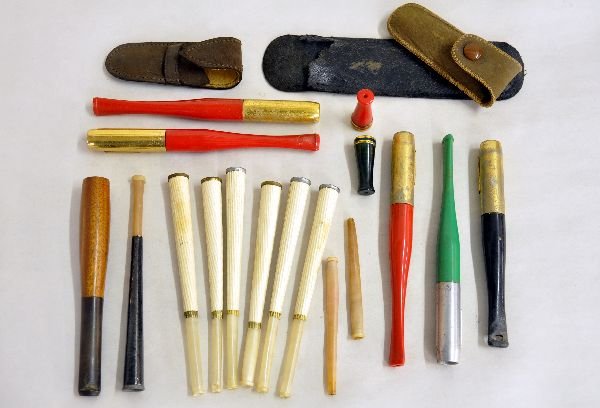 20 Assorted Cigarette Holders & Cases: Includes 4 4- 1/2" brass tip holders with colored handles with butt ejectors; 4" black & brass holder with butt ejector & several others, plus 3 empty leather pouches. All show signs of use & age. Exa