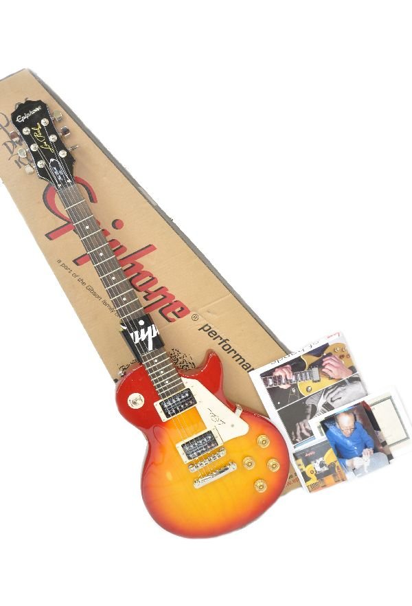 Signed Gibson Les Paul 100 Electric Guitar: Epiphone, Les Paul Model, hand signed on cream standard pick-guard. Signing photos enclosed with instruction manual. Serial 1112301819. Made in Indonesia. Heritage Cherryburst body with ebony & chrome