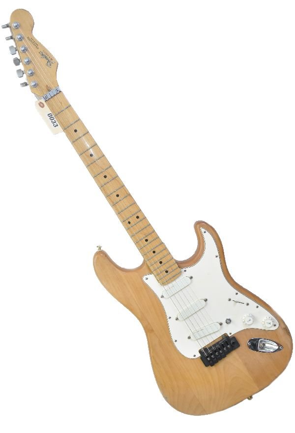 Fender Stratocaster US MADE: S/N E958279. Guitar is in a natural oiled wood finish with cream pickguard and knobs. Considerable play wear throughout and small hairline crack in neck of body. Missing knob end on pickup selector sw