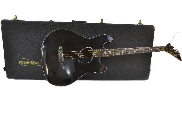 Kramer Ferrington Acoustic Electric Bass Guitar: S/N FB7234. Comes in a gloss black finish with pearl fret board inlays. Guitar shows moderate pick rash, and finish checking around the cord jack. Missing treble and bass switch knobs but switches app
