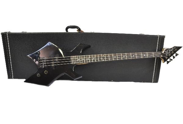 B C Rich Warlock Bass Guitar: S/N 12720. Guitar is in a gloss black finish. Environmental damage to hardware and frets. Minor fret and play wear. 3 small gashes on top edge of body. All knobs appear to be functional. Neck appears 