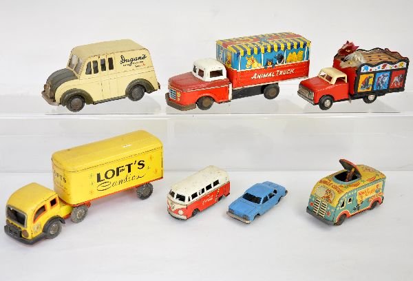 7 Vintage Tin Toy Vehicles: Includes a scarce 7" Dugan's dairy Divco truck; Lofts Ice cream tractor trailer; animated circus van; Coca-Cola VW bus; SN Japan animal truck, missing back door; small Corvair, all Japanese tin, Plus 