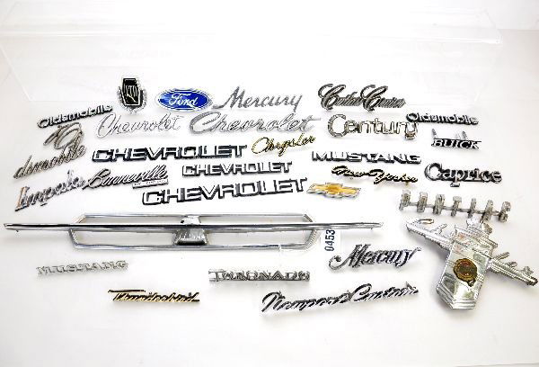 25+ Vintage Automobile Emblems: Nice assortment with some early examples up through the plastic age from Chrysler, Pontiac, Buick, Ford, Chevrolet & others. One Oldsmobile plate is broken, otherwise all appear complete. Grade ranges