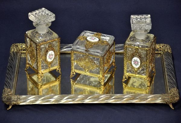 Early Ornate Dresser Set: 15 1/2X 9 1/2 glass mirrored tray. It has pressed glass twist pattern sides with pierced brass corner ornaments. The 3 matching pressed glass containers have their original tops with hand painted porc
