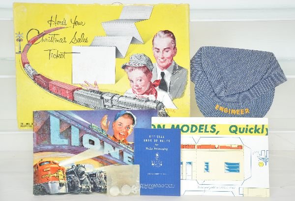Rare 1952 Lionel Christmas Packet: Interesting presentation including a 1952 consumer catalog; engineer hat with tin bend pins; paper village with Sunoco station. All items are mint, unused with an oversized color envelope that shows s