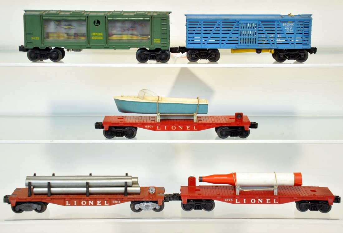 5 Lionel Freight Cars: Includes a 3435 aquarium car; scarce 3386 giraffe car, car only; 6175 flat with rocket and hold-down; 6801-50 flat with blue boat and hold-down; 6511 flat with pipes. All show light to moderate playwe