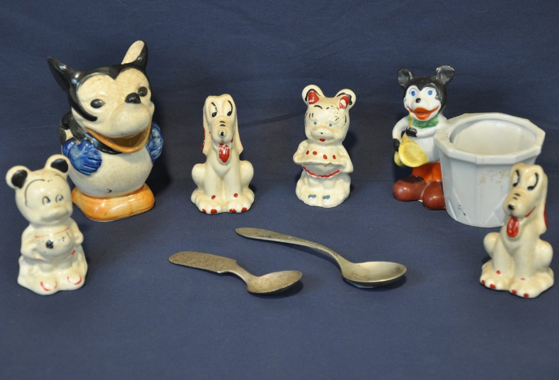 Early Mickey Mouse China & Spoon Lot: Circa 1920s-30s. Includes a 4 1/2" creamer, some crazing to glaze; cup holder; 2 Pluto & Mickey & Minnie figurines; 2 early pie-eyed Mickey silver plate baby spoons. All show moderate wear, but intact