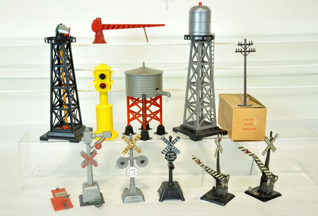 Assorted Marx Accessories: Includes banjo signal; bell signal; 2 auto crossing gates; street light; water tank, plastic gate; flasher; boxed telephone poles; beacon, no top; bubbling water tank. All show light to moderate playw