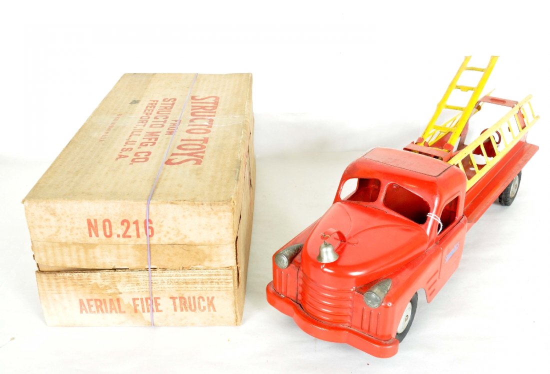 Structo Fire Ladder Truck & Box: Circa 1955. Painted and decaled pressed steel with rubber tires. 23 1/2" over-all length. Has its original bell and ladders. Top ladder cranks up and down, side ladders clip on. It is clean & shiny, b