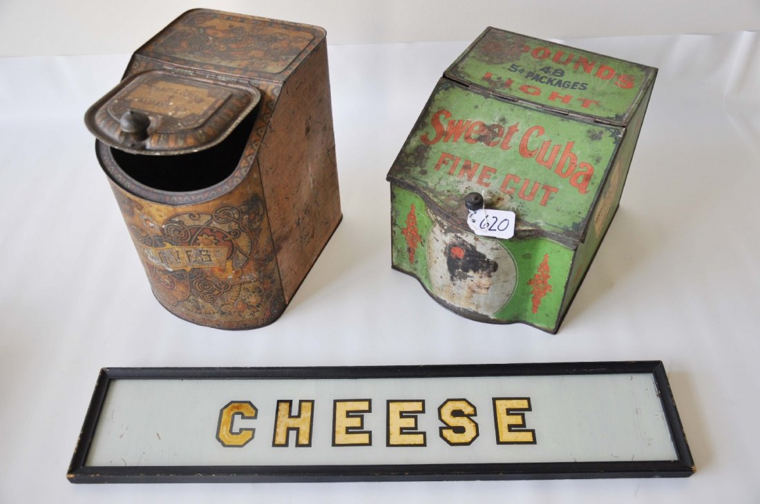 Country Store Tins & Sign: Includes a 22 1/2" reverse painted on glass Cheese sign from a counter display; 10" tall Cloves tin spice dispenser, color is faded; 8" tall Sweet Cuba tobacco dispenser with a few surface rust spots