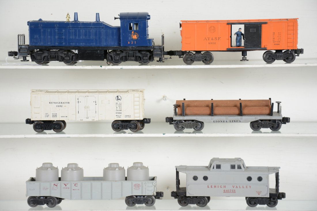 6Pc Lionel 621 Diesel Freight Set: Includes a 621 JC NW2 diesel with horn. Hairline screw crack with 100% decals; 3464 SF operating boxcar; 6482 reefer; 6411 flat with logs; 6562 gray gondola with replaced canisters; 6417 LV N5c Caboos