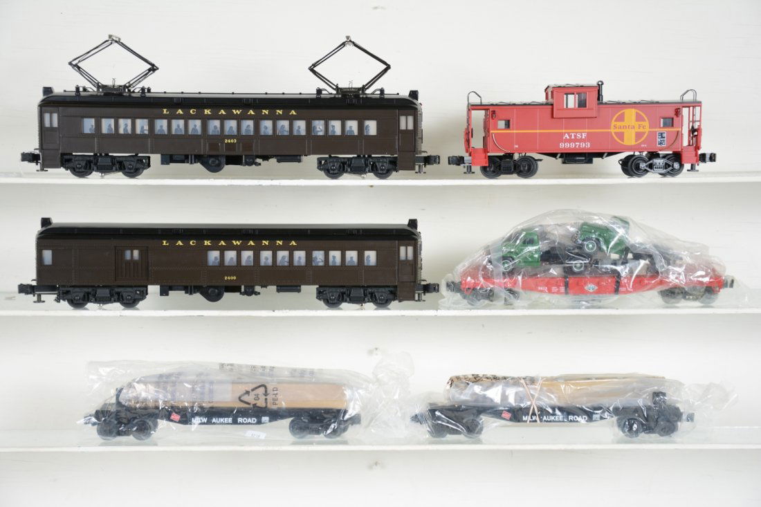 6Pc Lionel MTH Lot: Includes a Lionel Lackawanna MU AA set, lightly run; 2 #26680 MR flats with truss load; 9823 flat with Macks; MTH AT&SF caboose, cars are unrun, some have wrapping, C8+-10