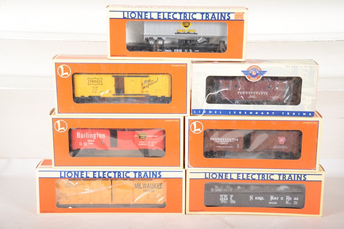 Lionel Deluxe Freight Cars: Includes 29266 Frisco boxcar; 17223 MR boxcar; 29295 PRR boxcar; 26293 Burlington boxcar; 17407 NPR gondola with scrap; 19415 flat with trailer; 29706 PRR Celebration caboose. All appear new in boxes,