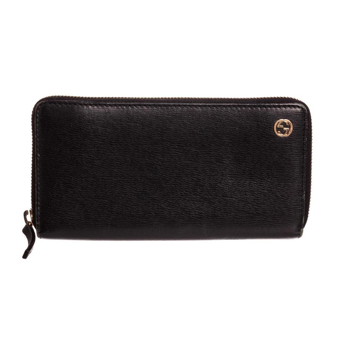 Gucci Black Leather Long Zippy Wallet: Black leather Gucci long zippy wallet with gold-tone hardware, tonal leather lining, three open compartments, one zipper pocket, twelve credit card pockets and overall zipper closure. Dimensions = 7.5