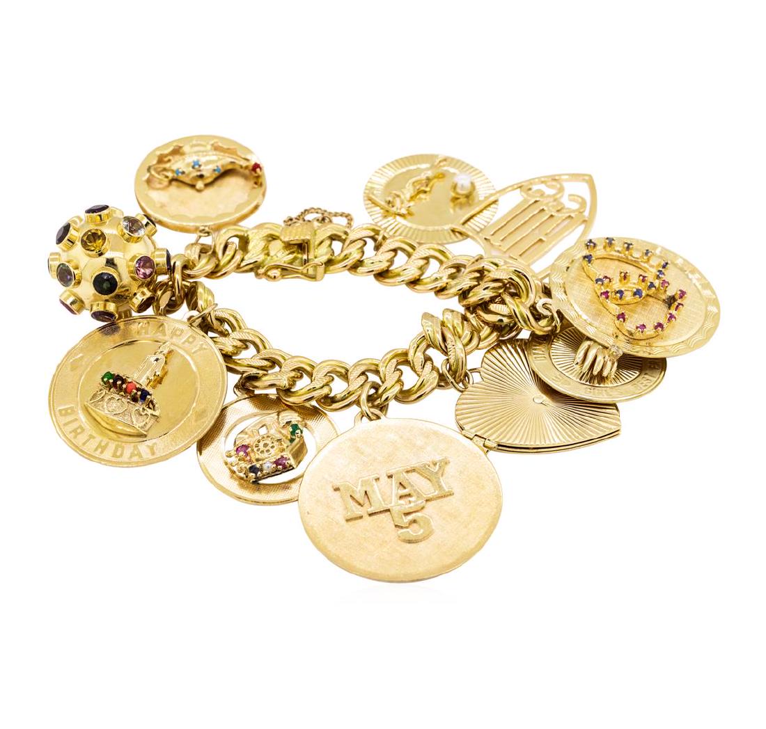 Charm Bracelet with Ten Attached Charms - 14KT Yellow: One charm bracelet measuring seven inches in length with ten attached charms and a safety chain featuring: 14KT yellow gold weighing 113.5 grams.