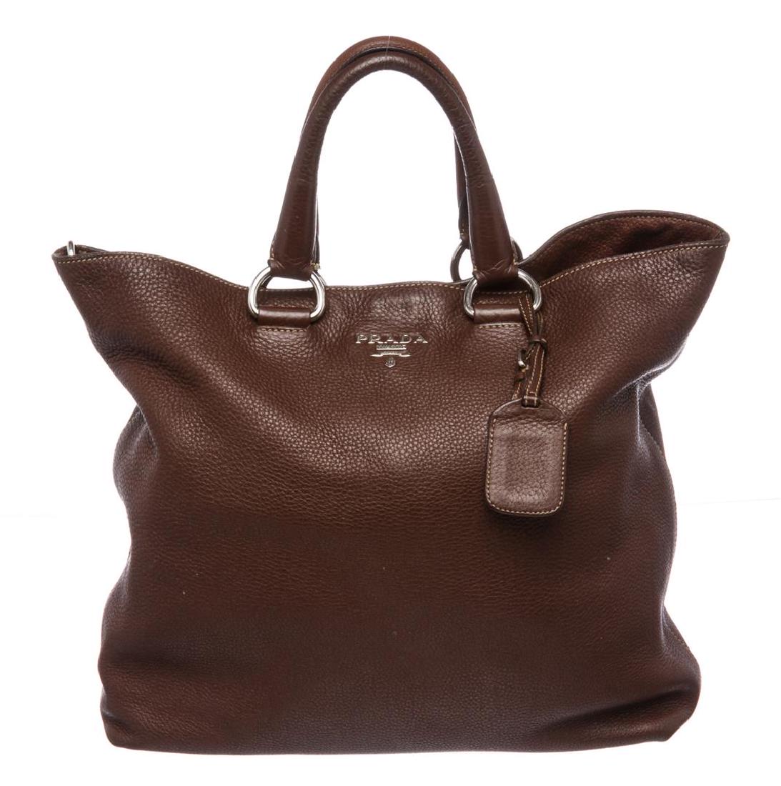 Prada Brown Pebbled Leather Tote Satchel Bag: Crafted out of brown pebbled leather. This handbag has double rolled handles, front metal logo tag, and inner logo fabric lining.