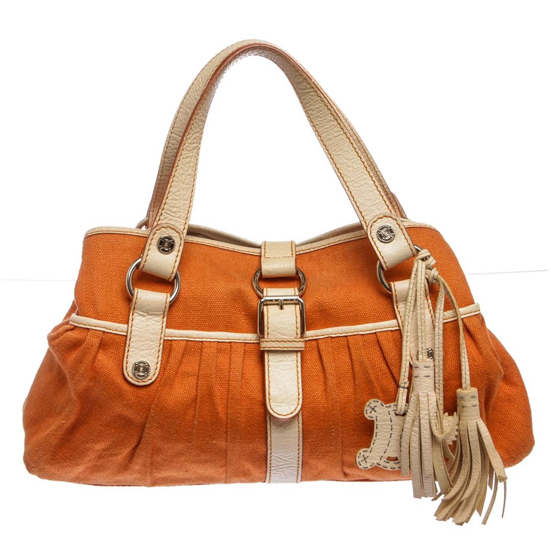 Celine Orange Canvas Leather Shoulder Bag: Orange canvas and Ivory leather trim with gold-tone hardware, dual flat leather handles, stamped button embellishments, leather hanging tassel, fabric lining with two pockets at interior wall; one wit
