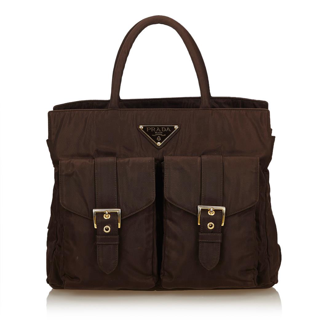 Prada Nylon Handbag: One Prada Nylon Handbag. This handbag features a nylon body, exterior flap pockets with belt details, rolled handles, and interior zip pockets.