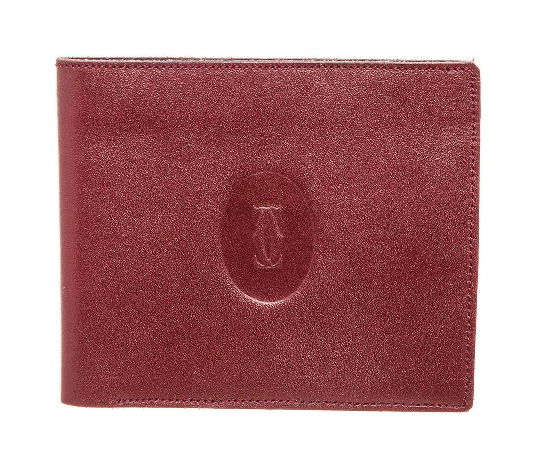 Cartier Burgundy Leather Bifold Wallet: Cartier burgundy leather bifold wallet with bill pocket, slit pocket, three card slots, suede pocket interior.