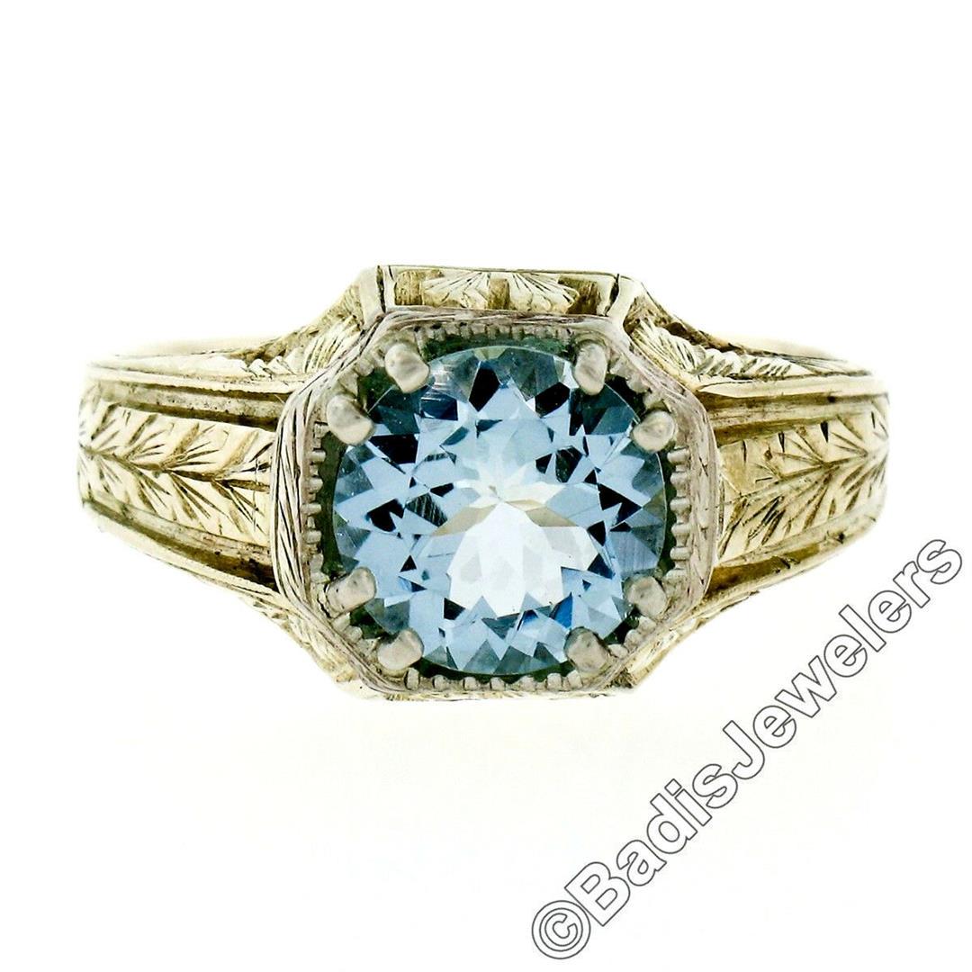 Art Deco 14kt Yellow Gold 1.45 ctw Round Aquamarine: A 14kt yellow and white gold art deco period solitaire ring featuring a 1.45ct round aquamarine and ornate etched patterns. The ring is size 7.5, weighs a total of 6.7 grams, and measures 11.0mm wide.