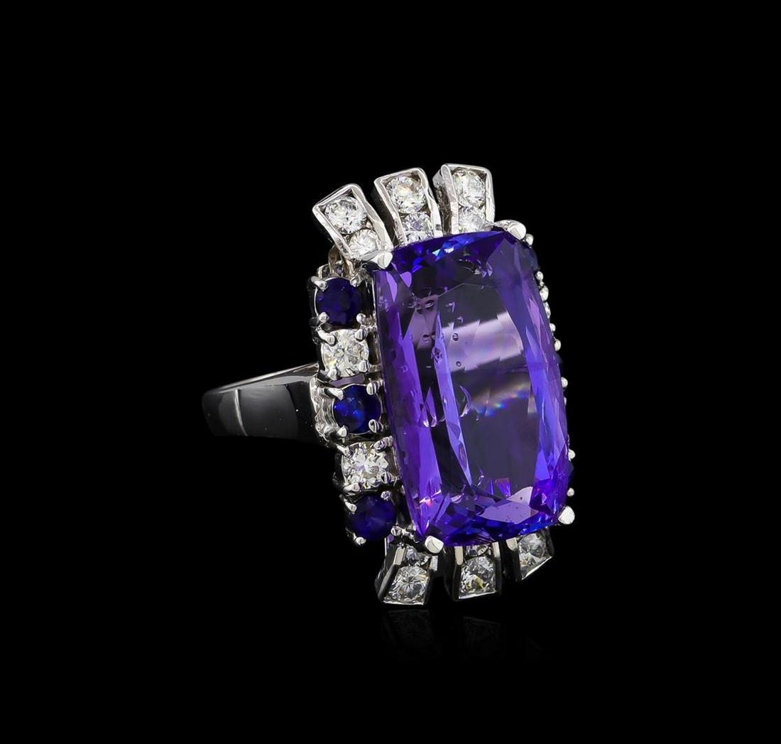 16.83 ctw Tanzanite, Sapphire and Diamond Ring - 14KT: One electronically tested 14KT white gold ladies cast tanzanite, sapphire and diamond ring with a bright polish finish. The featured tanzanite is set within a stylized sapphire and diamond bezel suppo