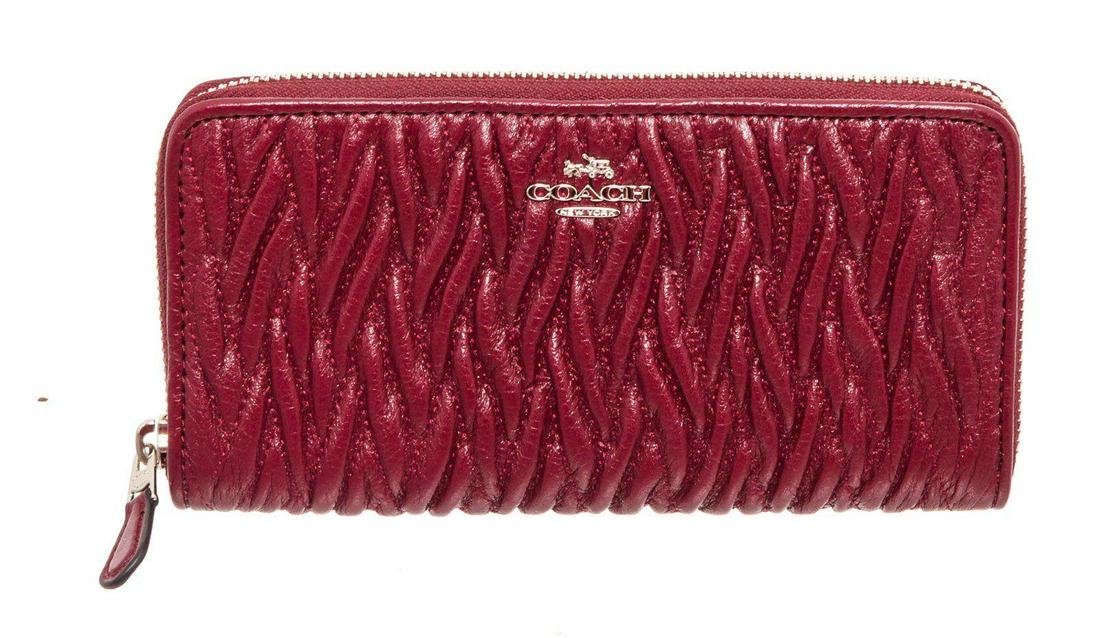 Coach Red Leather Zippy Wallet: Coach red textured leather zippy wallet with silver-tone hardware, logo placard at front, five interior compartments; one with zip closure, twelve cardholder slots and overall zip around closure. Meas