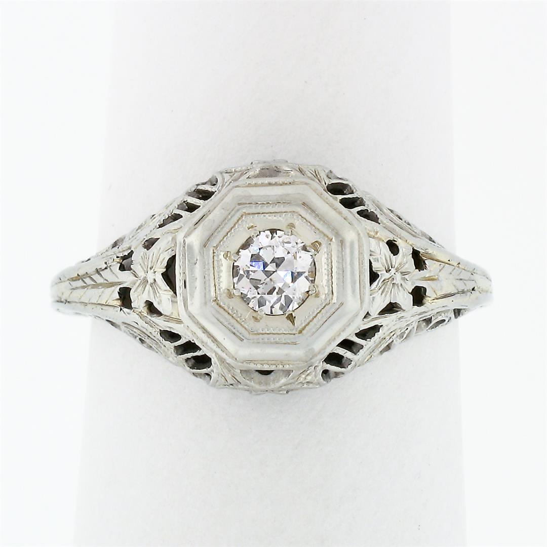 Antique Art Deco 18k White Gold .21 ctw Diamond: An 18k white gold art deco period ring featuring an old European cut diamond (G - SI1; 021ct) bead set at its center accented by floral etching and open filigree work throughout the gallery and shank.