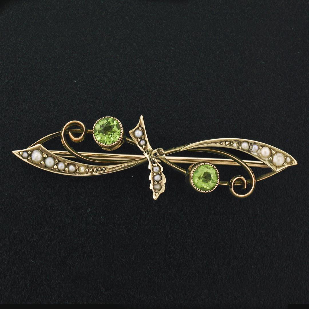 Antique Victorian 9k Gold Old Round Cut Peridot & Seed: A 9k yellow gold Victorian era brooch featuring a pair of old round cut peridots (4.50mm; 0.70ctw) accented by 17 round seed pearls (1.10mm to 2.35mm). Measures 13.5x46.5mm and weighs a total of 3.41 