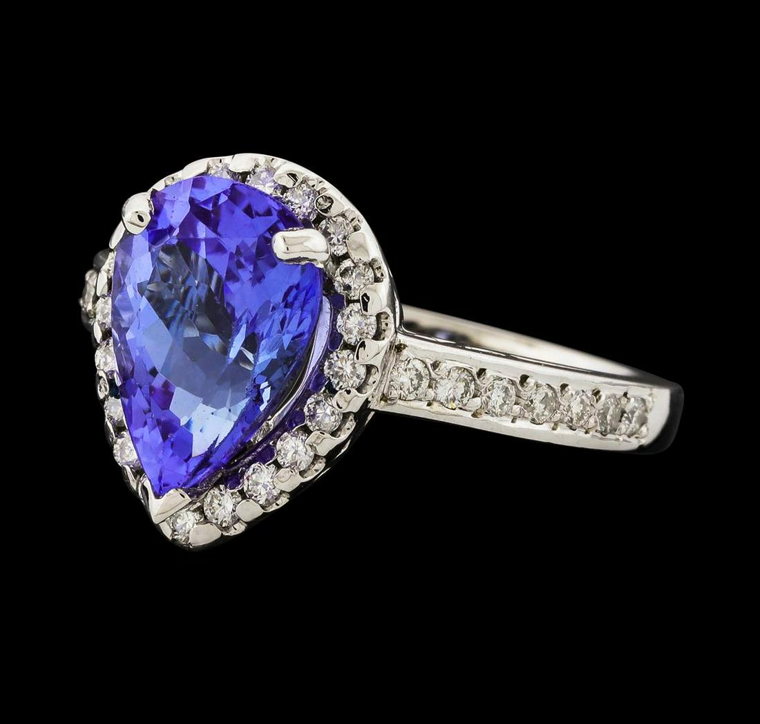 3.07 ctw Tanzanite and Diamond Ring - 14KT White Gold: One electronically tested 14KT white gold lady's cast fashion ring with a cathedral shank with a halo with a bright polish finish. The featured lady's ring has a shank measuring 2.22 millimeters wide.