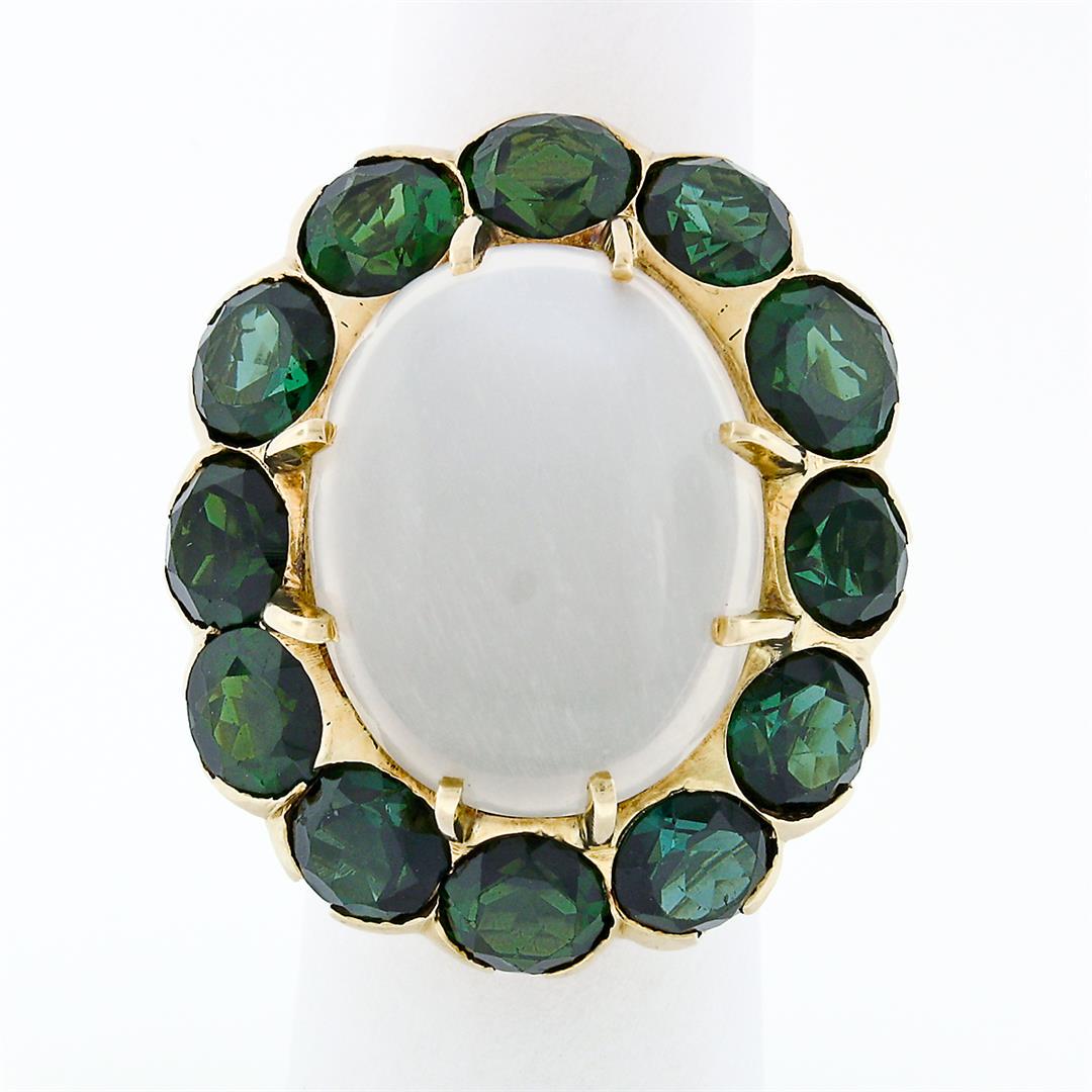 Vintage 14k Gold Large Oval Moonstone Solitaire Round Green Tourmaline Halo Ring: A vintage solid 14k yellow gold statement ring with 1 large oval cabochon cut natural moonstone (21.23x16.91mm), surronded with a halo of 12 round brilliant cut natural tourmalines (18.00ctw). The rin