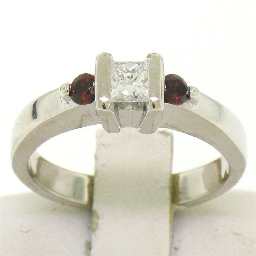 14k White Gold 0.41 ctw Princess Diamond and Garnet Engagement Ring: A 14k white gold engagement ring featuring a 0.25ct channel set princess cut diamond (F - VS1) flanked by 2 round brilliant garnets. The ring is size 5.0, weighs a total of 3.9 grams, and measures 5.1