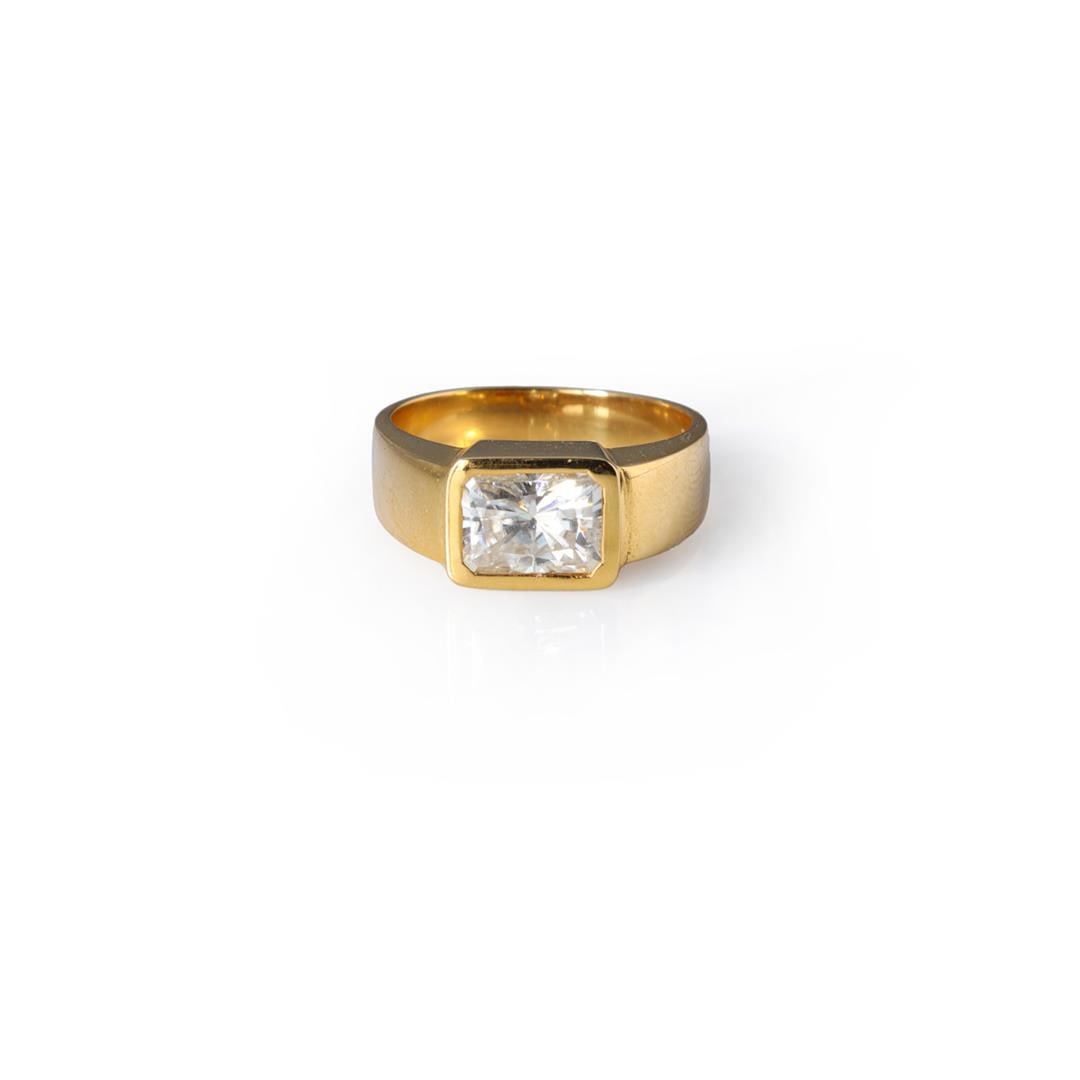 18k Yellow Gold & Moissanite Ring: Fine 18k yellow gold ring centered with a bezel set rectangular cut moissanite, interior band marked 750; gross weight 7.5 g, size 7 1/2