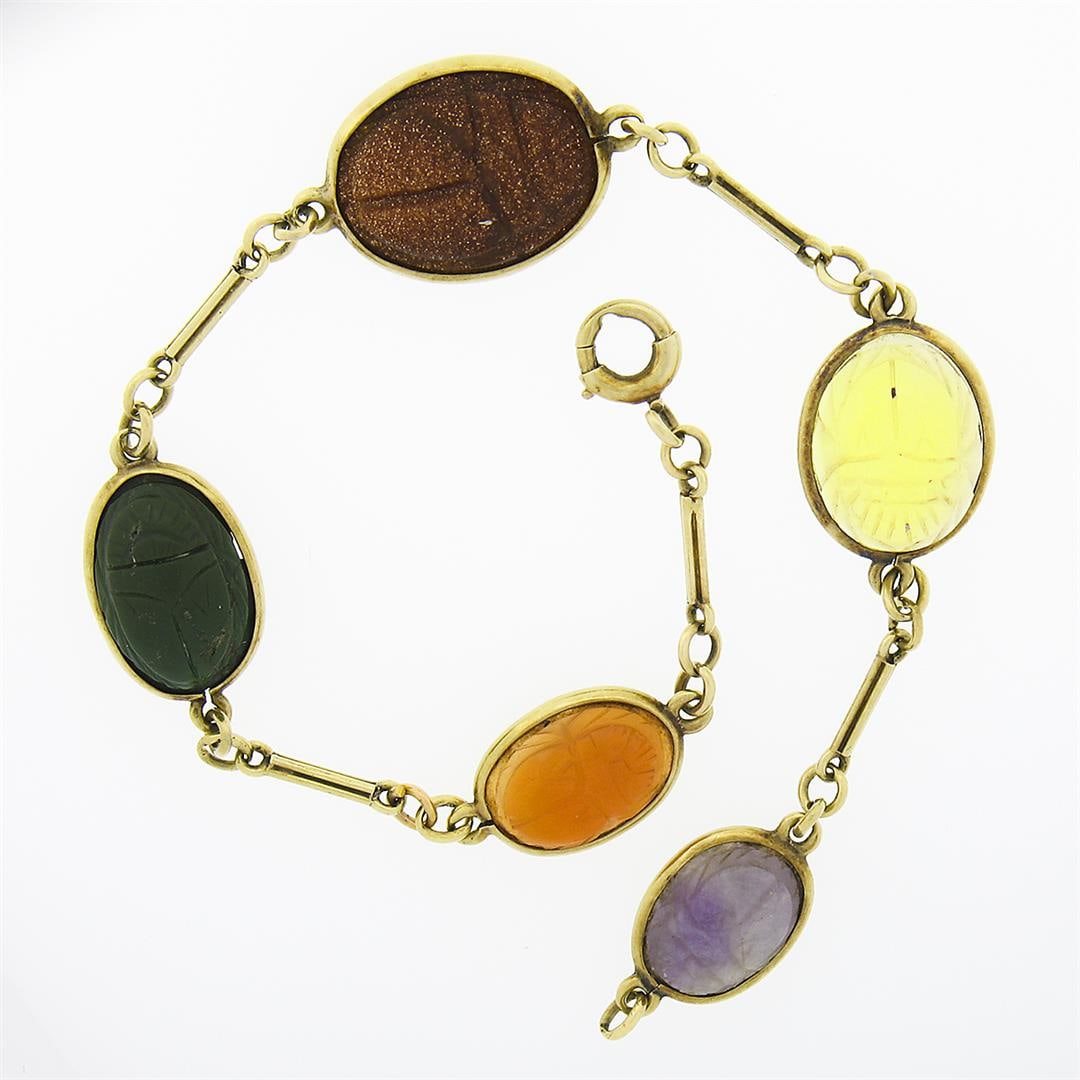 Antique Art Deco 14K Gold Graduating Scarab Carved Multi Gemstone Link Bracelet: An antique solid 14k yellow gold link bracelet, with 5 carved oval cabochon cut natural gemstones (14.5x11.1mm to 10x7.4mm). It weighs a total of 6.58 grams, measures 12.55mm wide, and measures 7 inch
